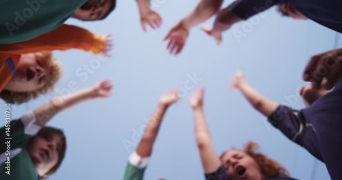 Coach leads a boy's youth soccer team in a team cheer.