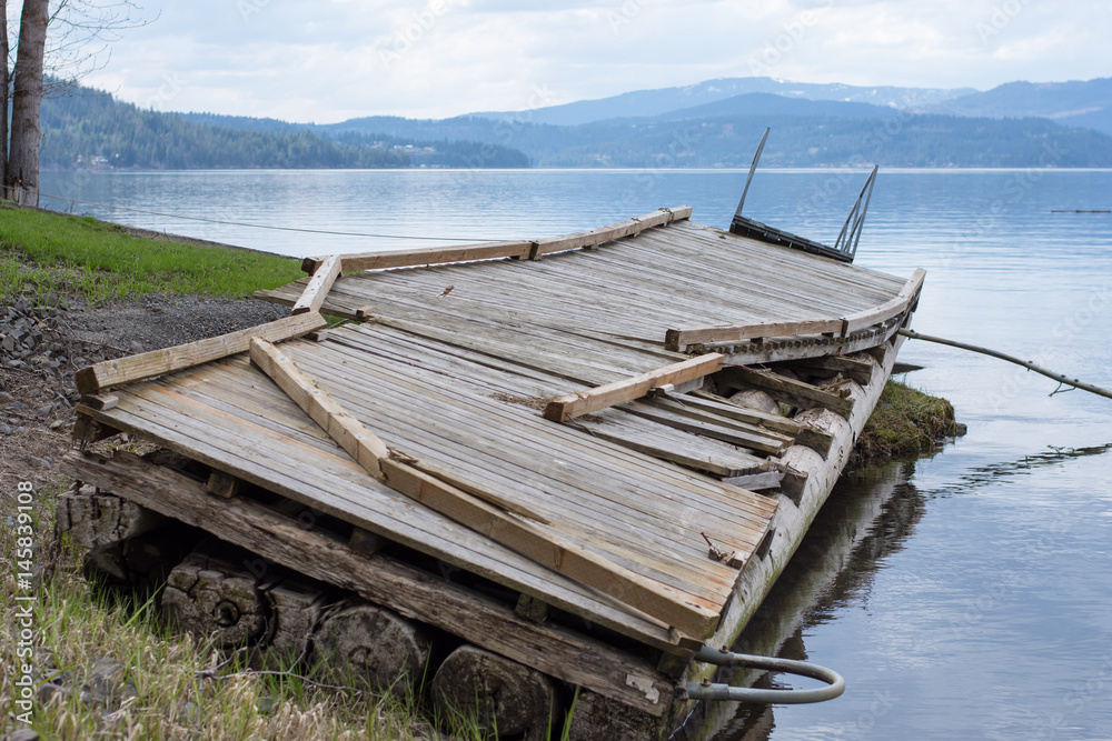 Large boat dock on the waters edge damaged from heavy winter snow and rain Large boat dock on the waters edge damaged from heavy winter snow and rain