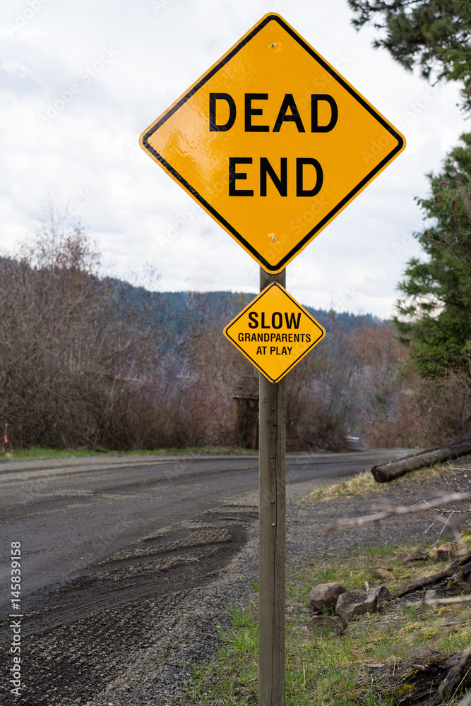 Yellow grandparents at play caution sign on rural road near a lake