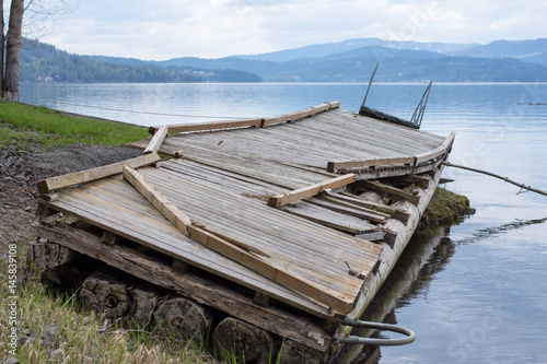 Large boat dock on the waters edge damaged from heavy winter snow and rain