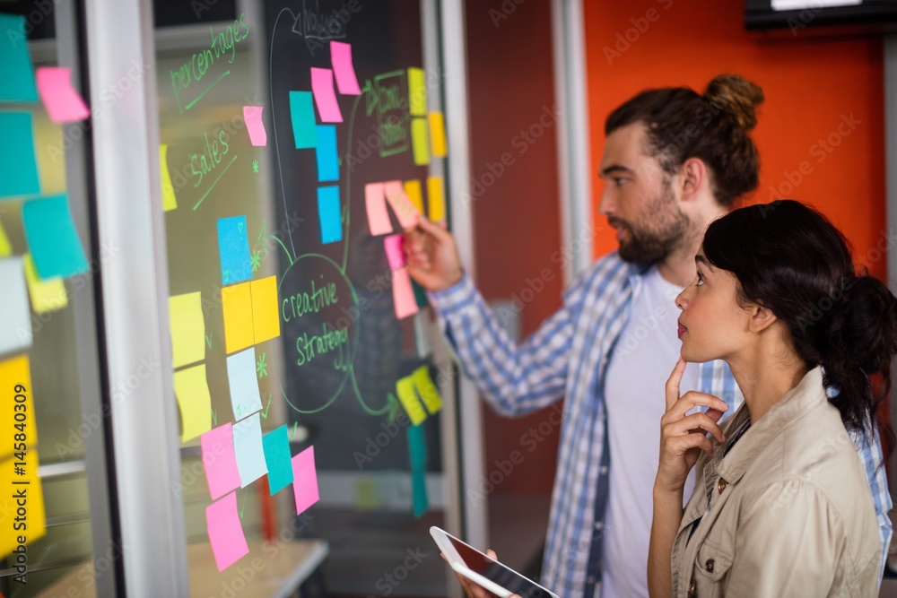 Fototapeta premium Male and female executives looking at sticky notes