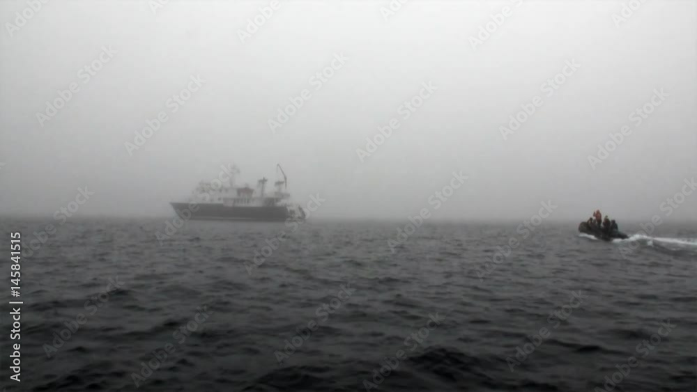 People in a boat sail to the ship in fog of Arctic Ocean in Svalbard. Wildlife in Nordic badlands. Unique footage on background natural landscape and snow of Spitsbergen. People in a boat sail to the ship in fog of Arctic Ocean in Svalbard. Wildlife in Nordic badlands. Unique footage on background natural landscape and snow of Spitsbergen.