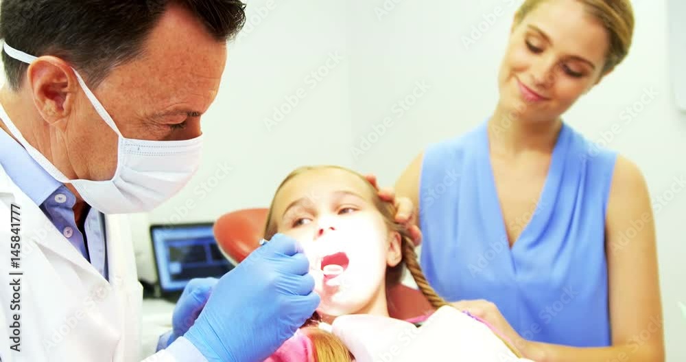 Dentist examining a young patient with a tool