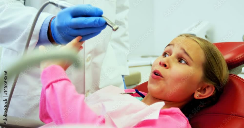 Girl stopping dentist for examining her in clinic Girl stopping dentist for examining her in clinic