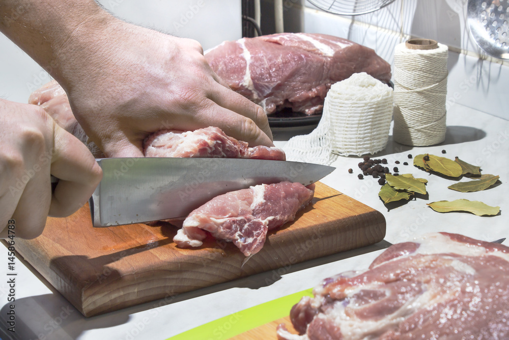 Krojenie surowego mięsa nożem kuchennym. Przygotowanie mięsa do wędzenia. Schab, karkówka