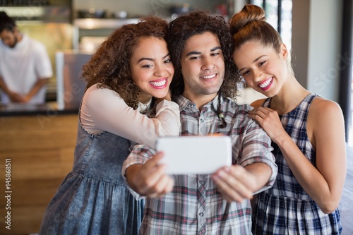 Man taking selfie with female friends in cafe