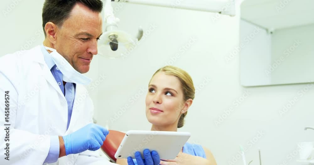 Dentist discussing over digital tablet with female patient Dentist discussing over digital tablet with female patient