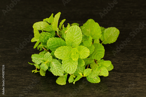 Green peppermint leaves on black background