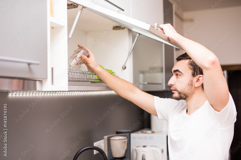 man arrange washing dishes in kitchen at home