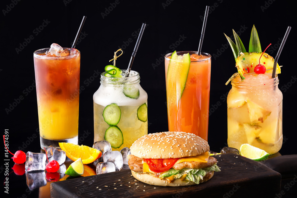 Φωτογραφία Group of fresh summer cocktails and burger at wooden board isolated at black background
