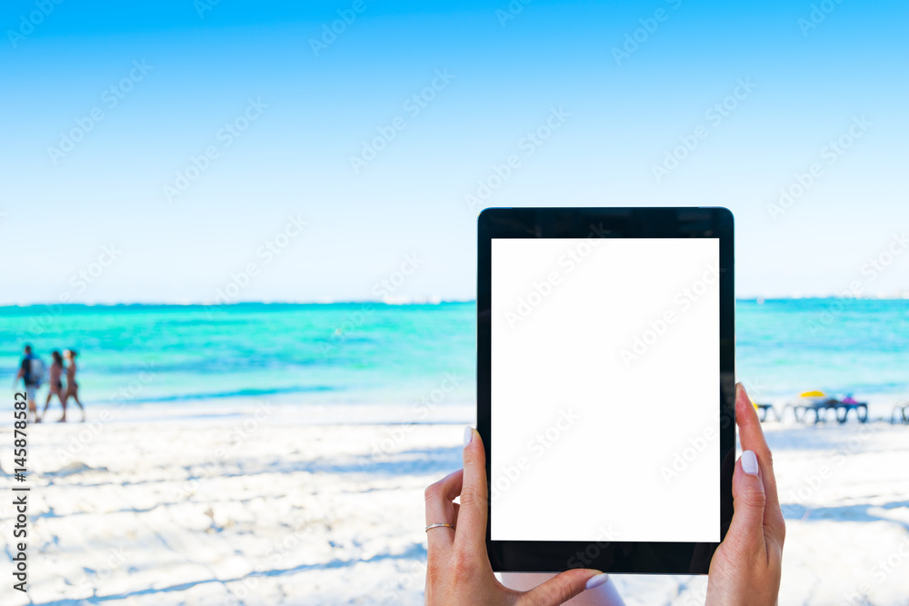 Blank empty tablet computer in the hands of girl on the beach