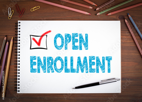 Open Enrollment. Notebooks, pen and colored pencils on a wooden table.