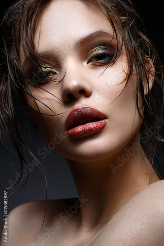 A young girl with bright creative makeup and perfect skin. Beautiful model with wet hair on face. Beauty of the face.