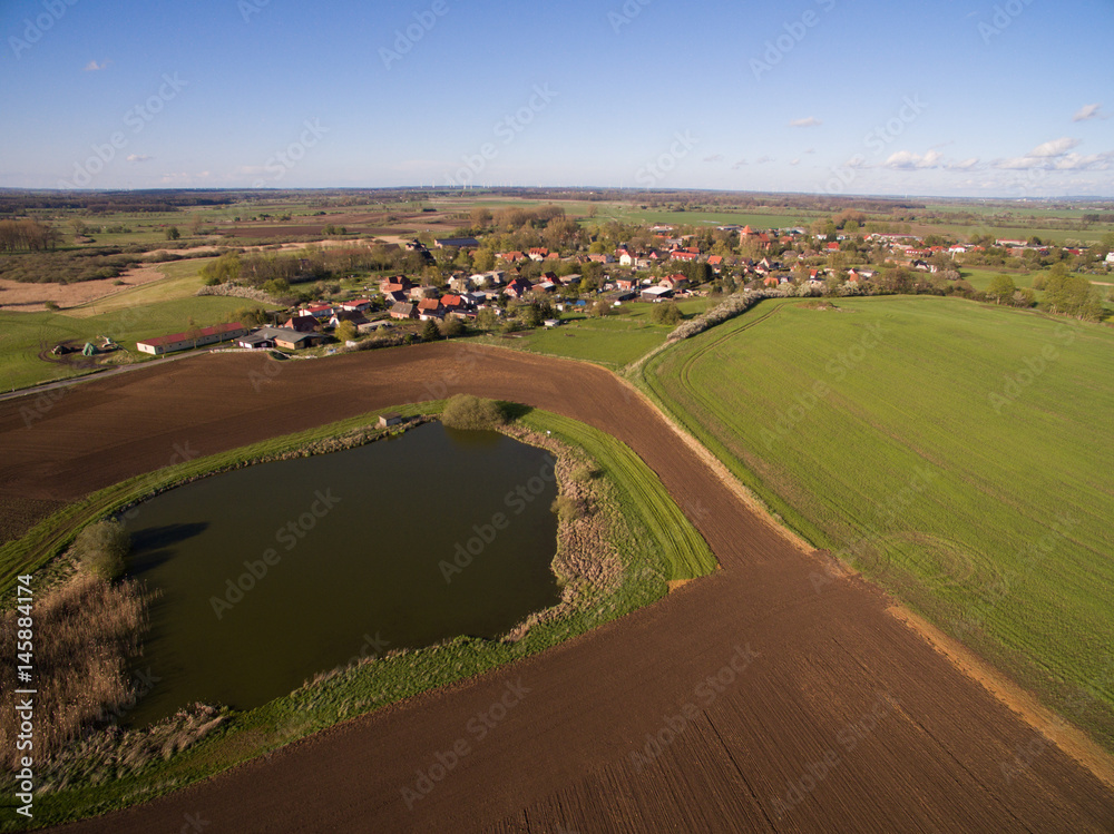 aerial view of a smal village with beautiful agricultural fields under blue sky - germany