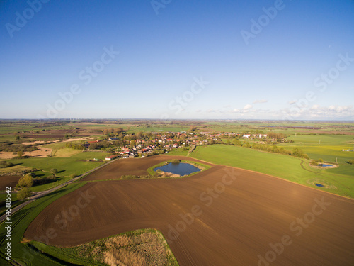 aerial view of a smal village with beautiful agricultural fields under blue sky - germany