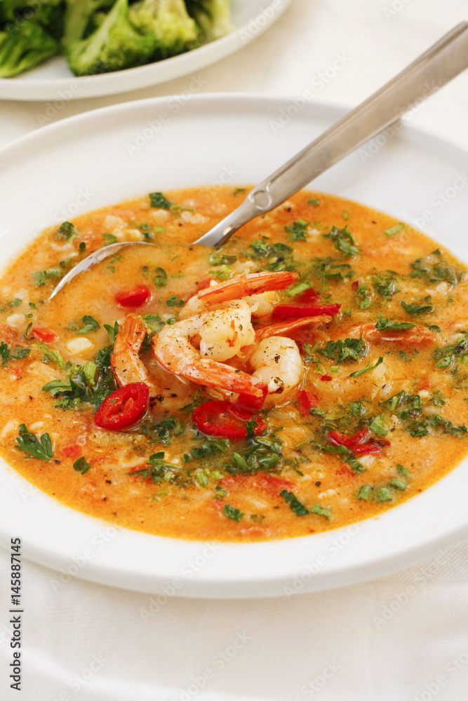 Hearty tomato soup with prawns on white platter Hearty tomato soup with prawns on white platter