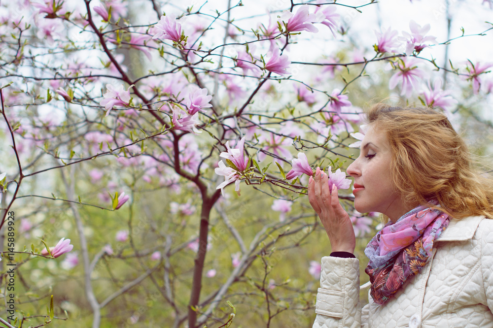 A romantic pretty woman walks in the environment of gentle pink flowers in the botanical park breathes a pleasant aroma of garden A romantic pretty woman walks in the environment of gentle pink flowers in the botanical park breathes a pleasant aroma of garden