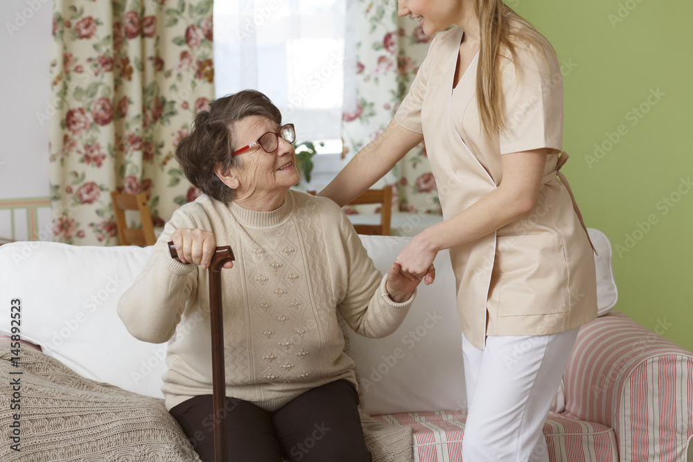 Fototapeta premium Caregiver helping senior woman