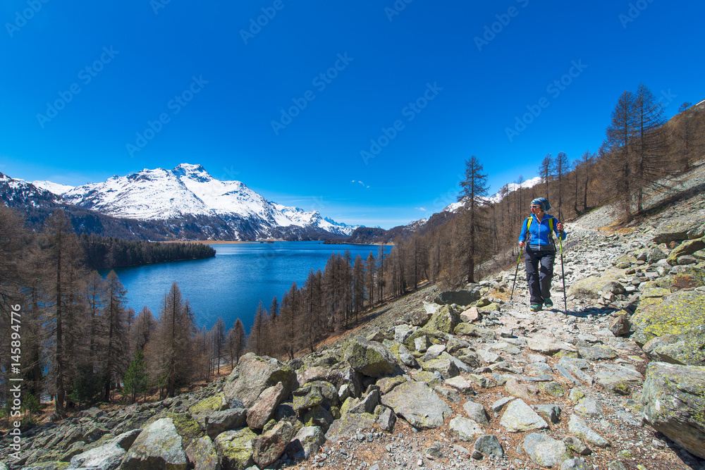 Alpine trekking on the Swiss Alps a girl hiking with a large lake in the background