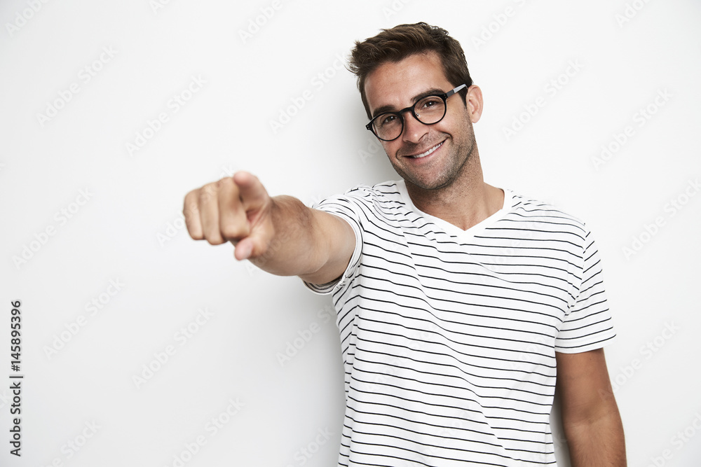 Portrait of guy pointing in studio, smiling Portrait of guy pointing in studio, smiling