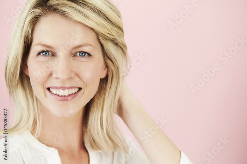 Blue eyed blond woman on pink background