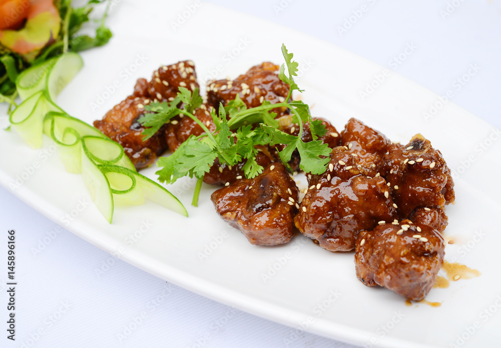 Sauteed pork ribs with seasame and herbs on white dish