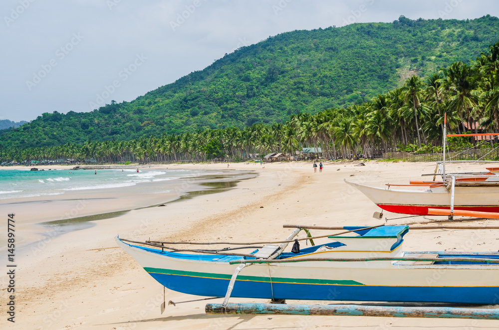 Local boats on Nacpan Beach on sunny day. El Nido, Palawan, Philippines