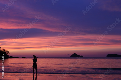 women stand on beach in sunset time, she feeling alone, no more people