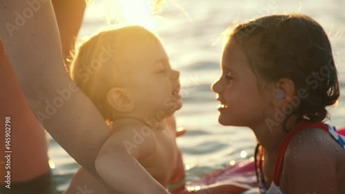 baby boy kisses baby girl at the ocean photo