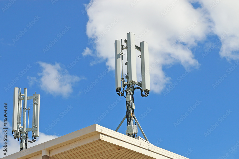 telephone exchange with cellular antennas on roof against blue sky telephone exchange with cellular antennas on roof against blue sky