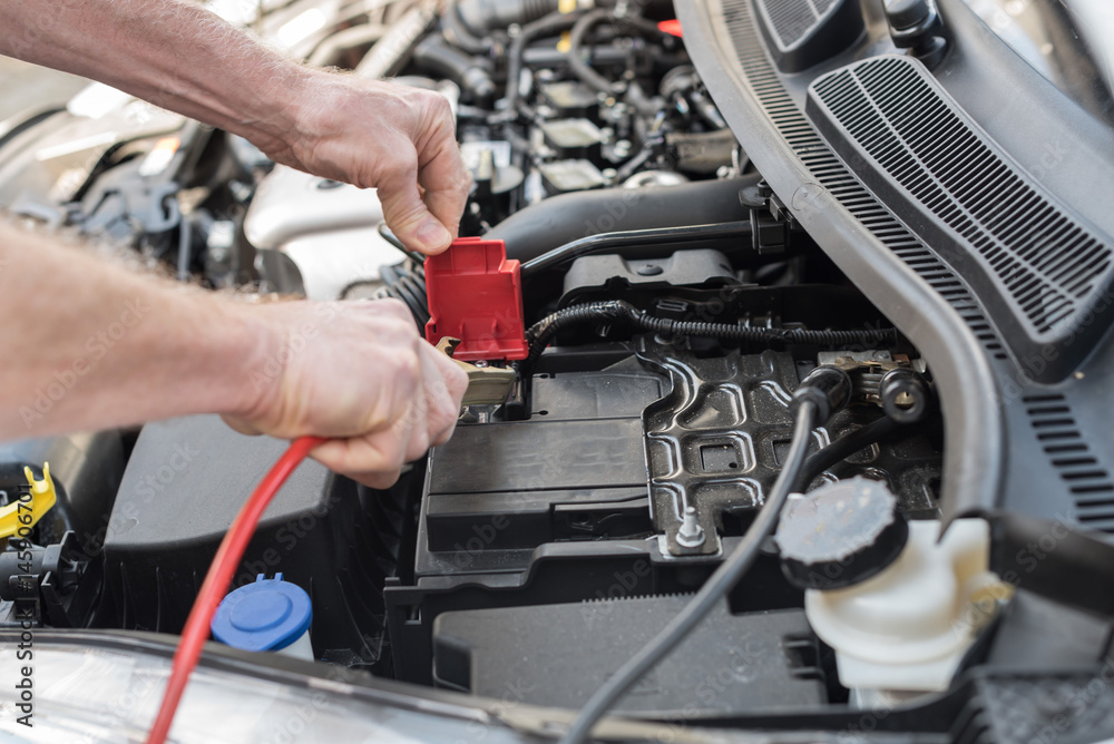 Hands of car mechanic using car battery jumper cable Hands of car mechanic using car battery jumper cable