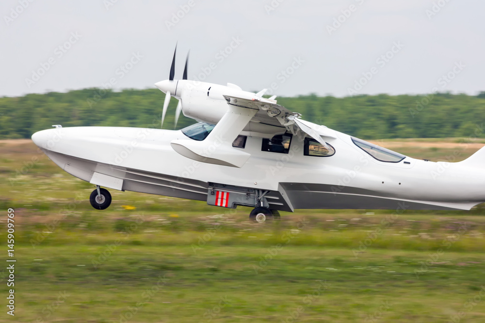 Amphibian airplane landing on the grass field Amphibian airplane landing on the grass field