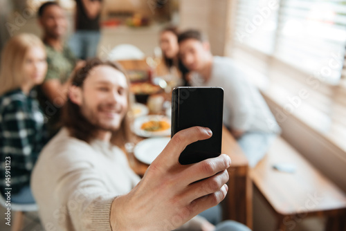 Man taking a selfie photo with friends in the kitchen