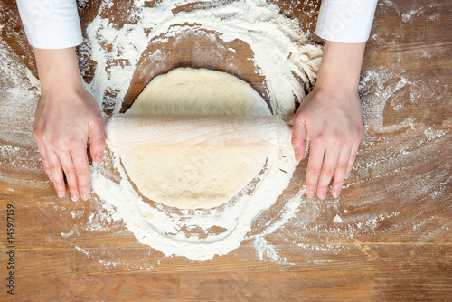 top view of child making pizza dough on wooden tabletop