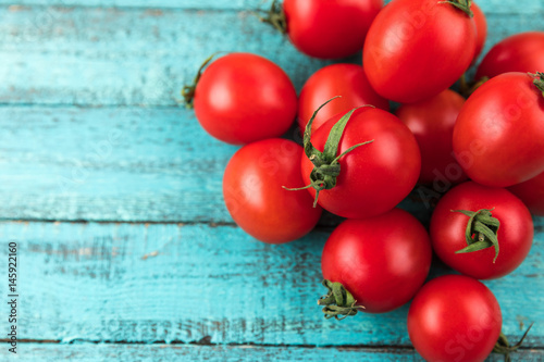 cherry tomatoes on turquoise wooden table top texture. fresh seasonal vegetables concept photo