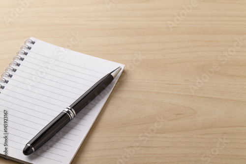 Note book and pen on the wooden table © Lau