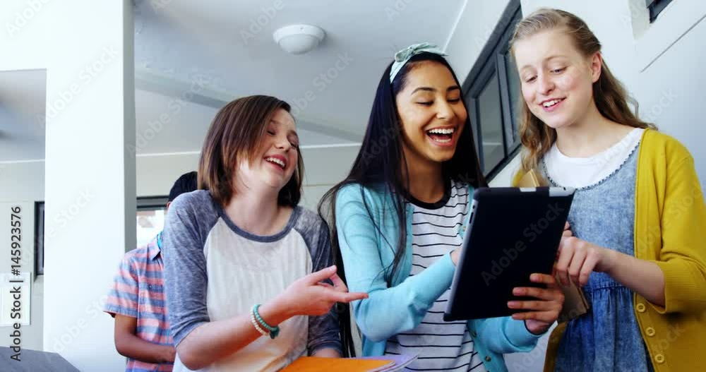 Group of school friends using digital tablet in corridor Group of school friends using digital tablet in corridor
