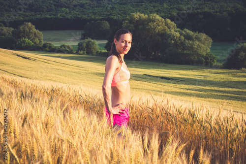 Beautiful runner girl in colorful sport wear in wheat field 