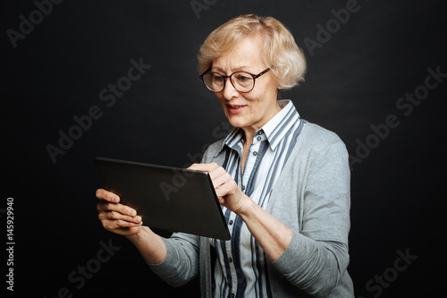 Cheerful old woman using electronic gadget in the studio © zinkevych