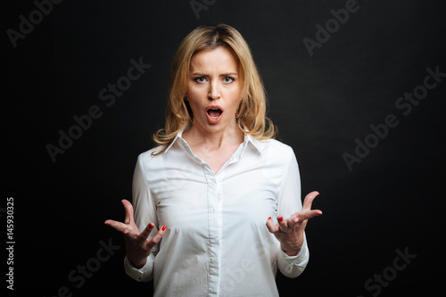 Quadro em tela Furious mature woman yelling in the black colored studio