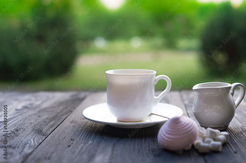 Сup with linden tea and flowers on wooden table in garden