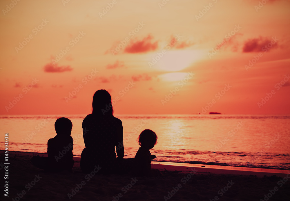 mother and two kids looking at sunset on beach mother and two kids looking at sunset on beach