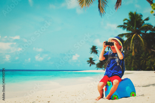 little boy travel on beach with suitcase