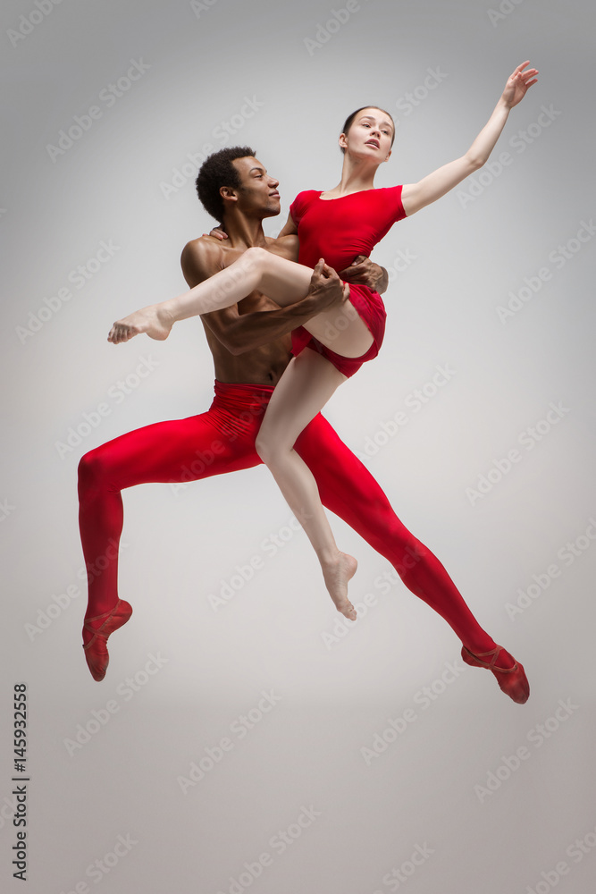 Fototapeta premium Couple of ballet dancers posing over gray background