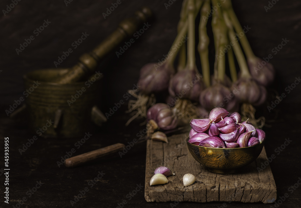Still life with fresh organic garlic placed in old copper bowl on rustic wooden background.Copy Space..