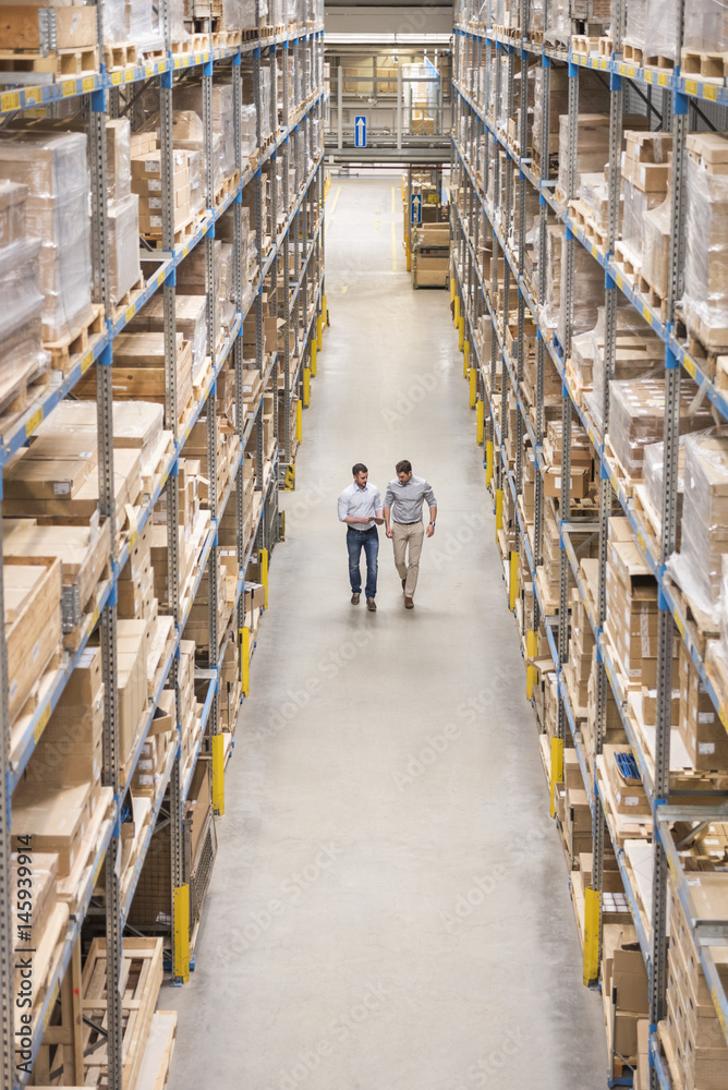 Two men walking in factory warehouse Two men walking in factory warehouse
