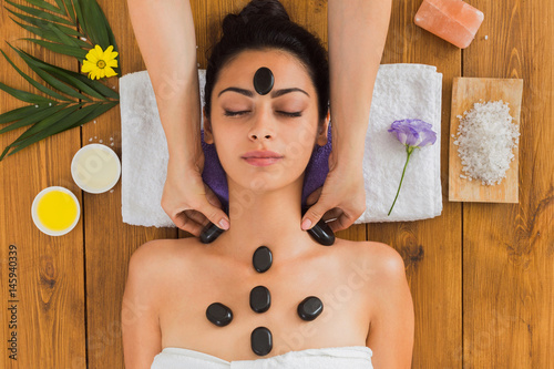 Beautician make stone massage spa for woman at wellness center