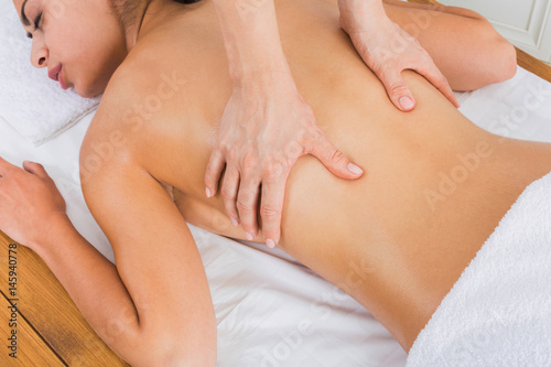 Closeup massagist hands make body massage in spa wellness center