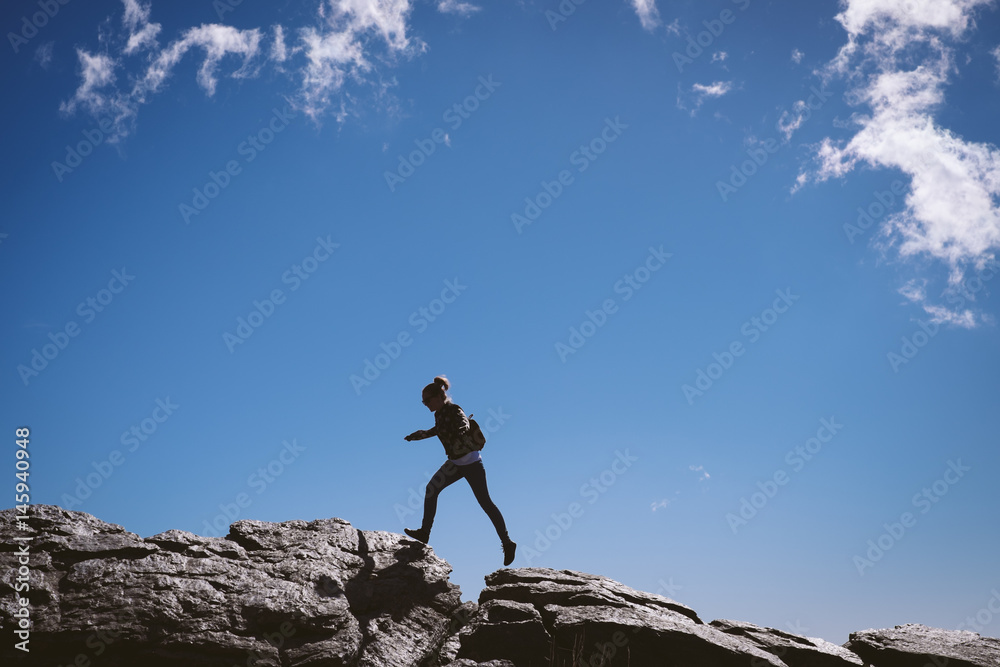 Woman jumping on top of a mountain.