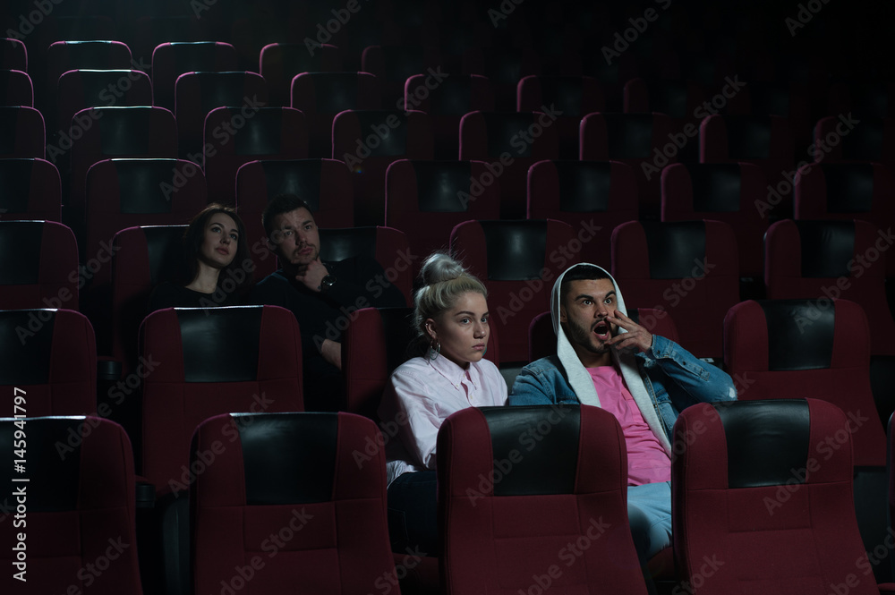 Group of young adults watching movie in theater Group of young adults watching movie in theater